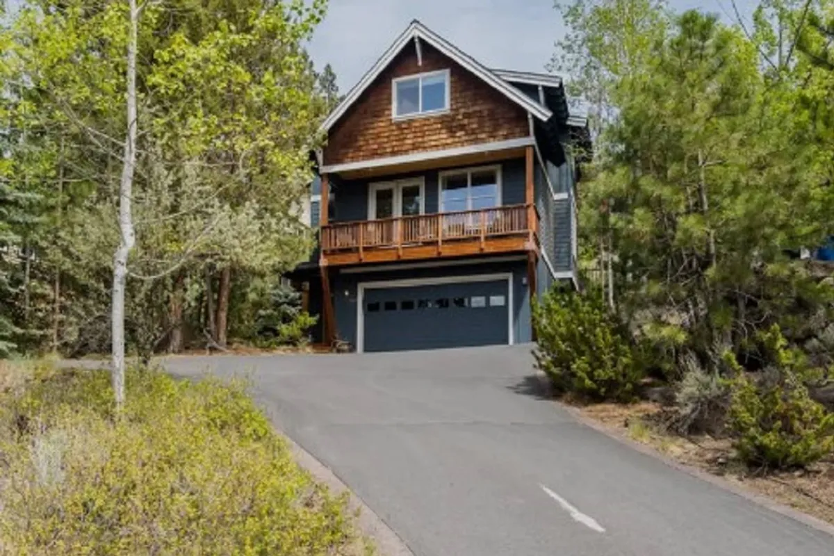 This image showcases the home's exterior, focusing on a welcoming wooden balcony and the stone and wood façade, surrounded by greenery. The inviting porch suggests a space for relaxing mornings with coffee or evening gatherings after adventures in town.