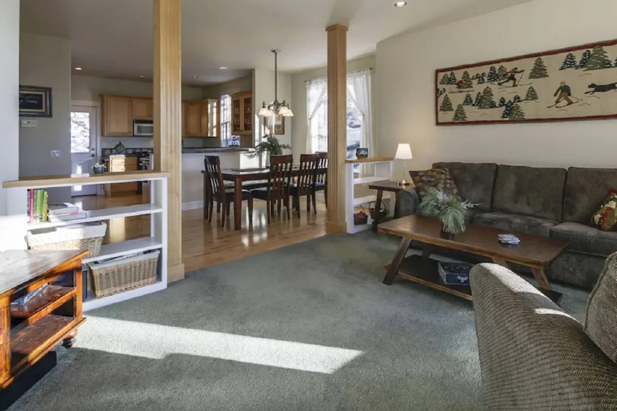 An inviting open-plan area with a plush sofa, a dining table set for a group, stylish wall art, and modern light fixtures. The space is clearly designed for gathering, dining, and unwinding with friends or family, echoing the section's emphasis on group experiences and shared meals.
